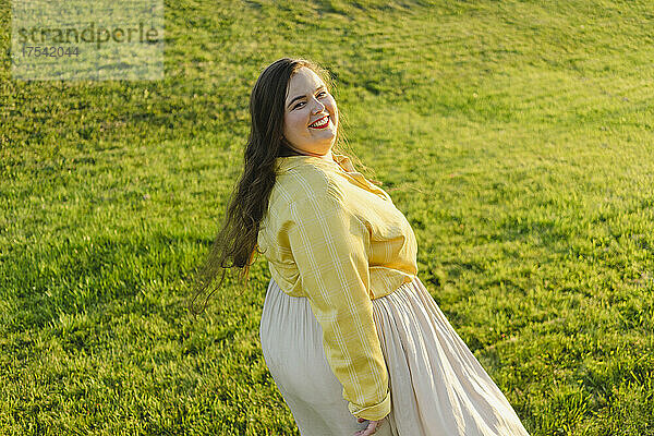 Smiling plus size woman looking over shoulder at sunset