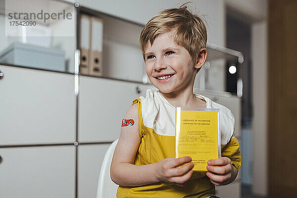 Smiling boy holding vaccination certificate at center