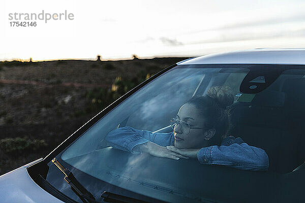 Woman with arms crossed looking through car windshield