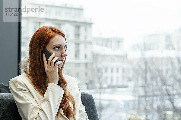 Geschäftsfrau telefoniert am Fenster im Büro