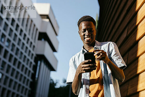Happy man using smart phone in city