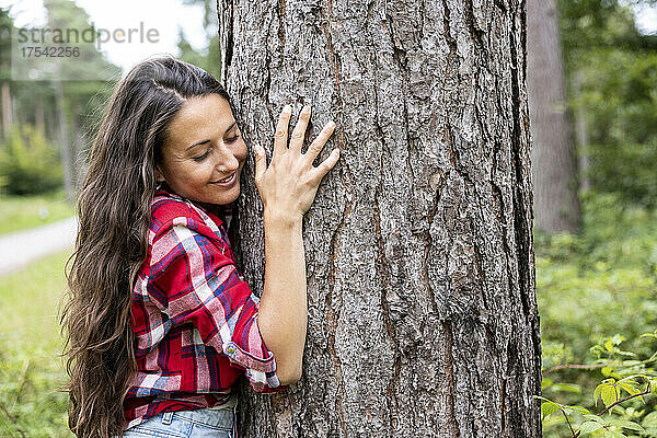 Smiling woman embracing tree at Cannock Chase