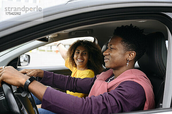 Smiling woman talking with friend driving car