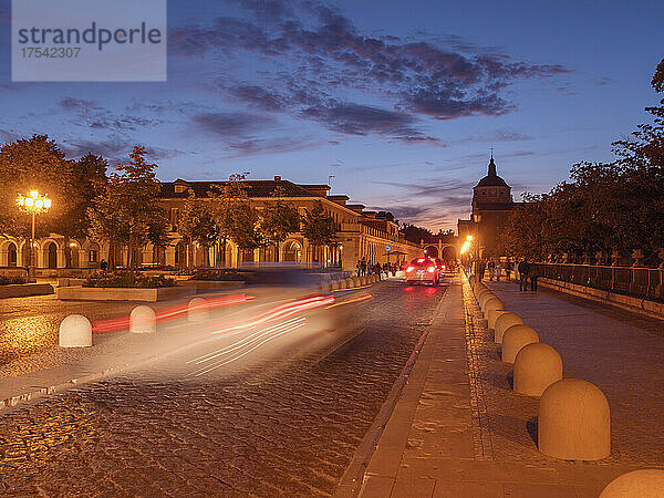 Spain  Community of Madrid  Aranjuez  Blurred motion of cars driving along cobblestone street at dusk