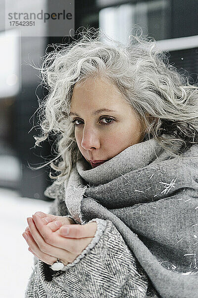 Frau mit grauem Schal fühlt sich im Winter kalt an