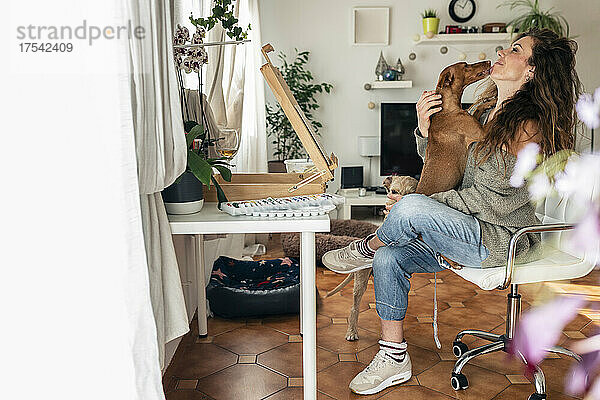 Maler sitzt mit Hunden auf einem Stuhl im heimischen Wohnzimmer