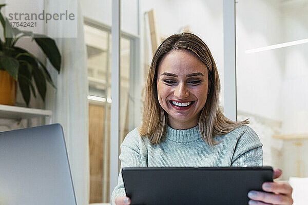 Happy businesswoman using tablet PC at studio