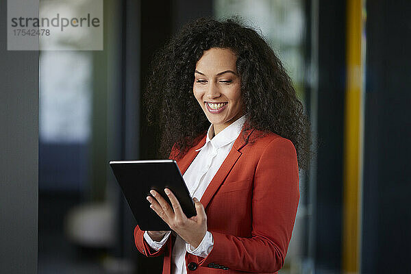 Glückliche Geschäftsfrau  die im Büro an einem digitalen Tablet arbeitet
