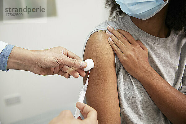 Arzt injiziert dem Patienten im Krankenhaus den COVID-19-Impfstoff mit einer Spritze in den Arm
