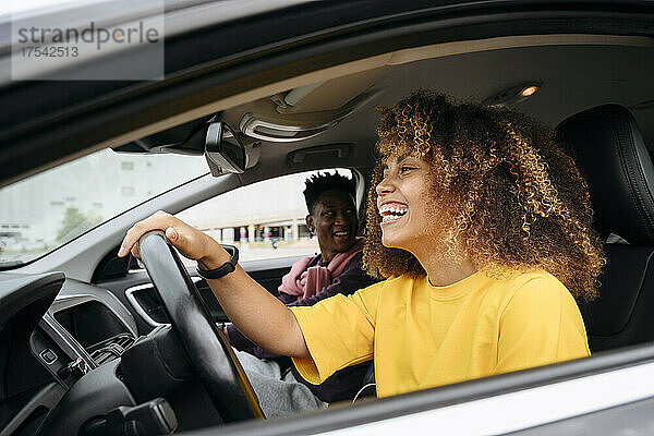 Fröhliche junge Frau mit Freundin im Auto
