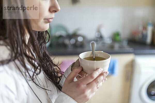 Frau hält Teetasse in der heimischen Küche