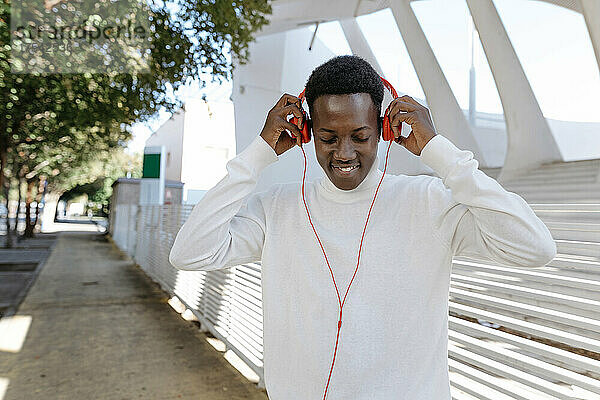 Smiling man wearing headphones on footpath