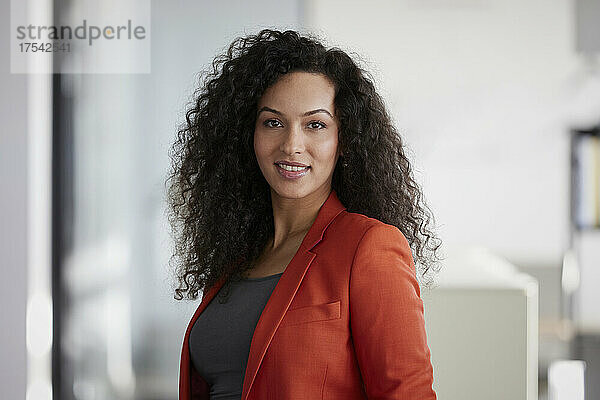 Smiling businesswoman with black curly hair in office