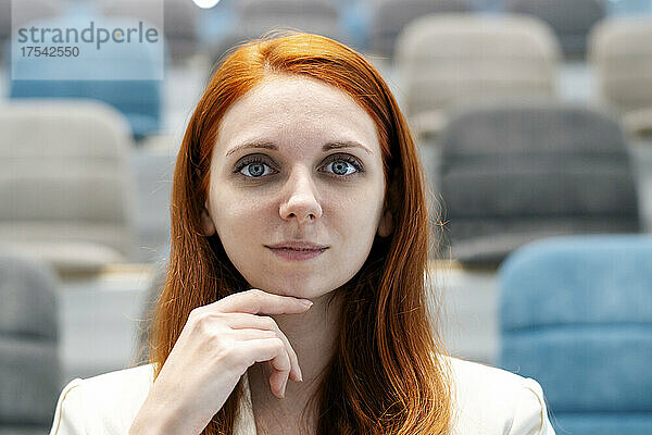 Redhead businesswoman with hand on chin at convention center in office