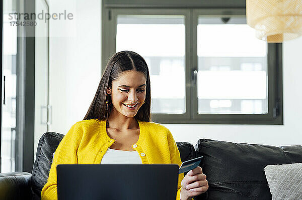 Smiling woman with credit card doing online shopping on laptop