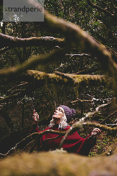 Woman with eyes closed and arms outstretched in forest
