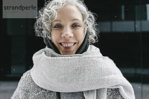 Happy woman wrapped in gray scarf