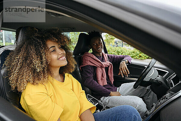 Smiling man looking at friend sitting in car