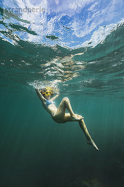 Sorglose junge Frau schwimmt unter Wasser
