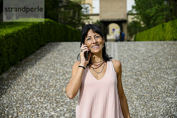Smiling woman talking through mobile phone on sunny day