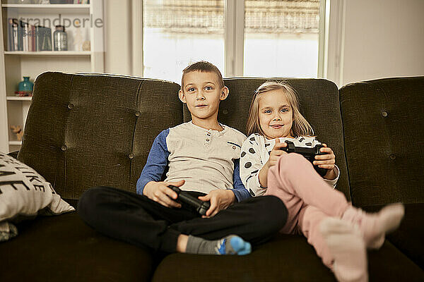 Sibling playing video game through joystick at home
