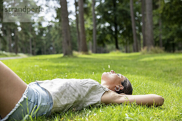 Frau mit geschlossenen Augen entspannt sich im Gras bei Cannock Chase