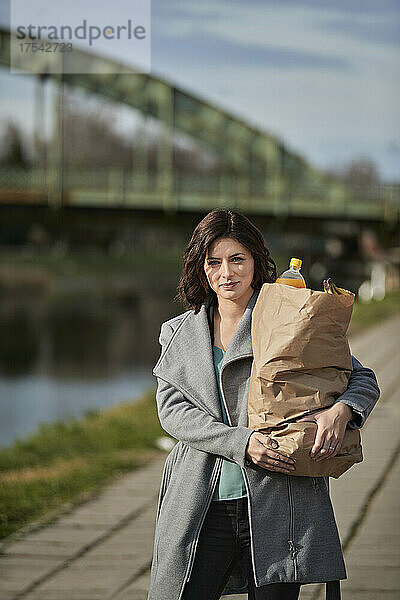 Woman carrying groceries in paper bag on footpath