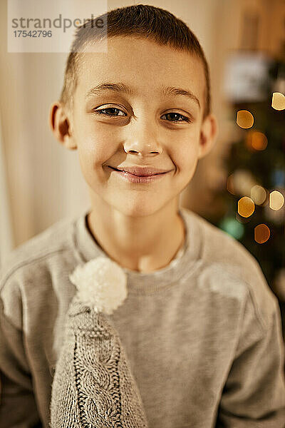 Cute boy smiling in front of christmas tree at home