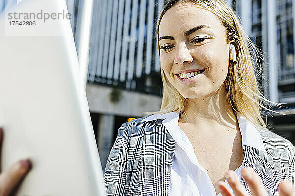 Lächelnde junge Geschäftsfrau bei Videoanruf über Tablet-PC