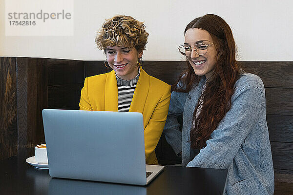 Lächelnde Geschäftskollegen nutzen Laptop im Café
