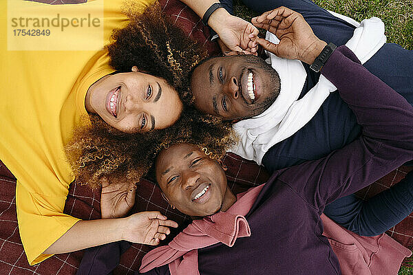 Smiling multiracial friends lying on blanket in park