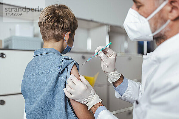 Mitarbeiter des Gesundheitswesens verabreicht einem Jungen im Impfzentrum den COVID-19-Impfstoff