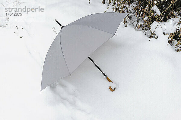 Open umbrella fallen on white snow