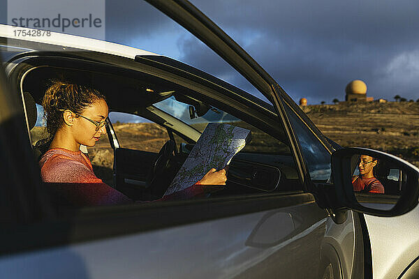 Junge Frau hält Karte im Auto