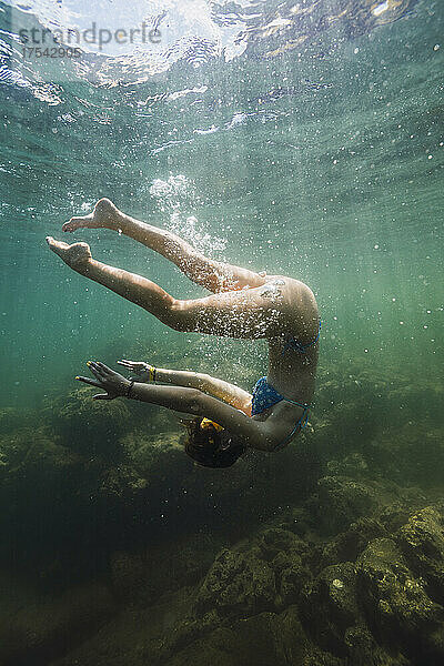 Carefree young woman flipping undersea