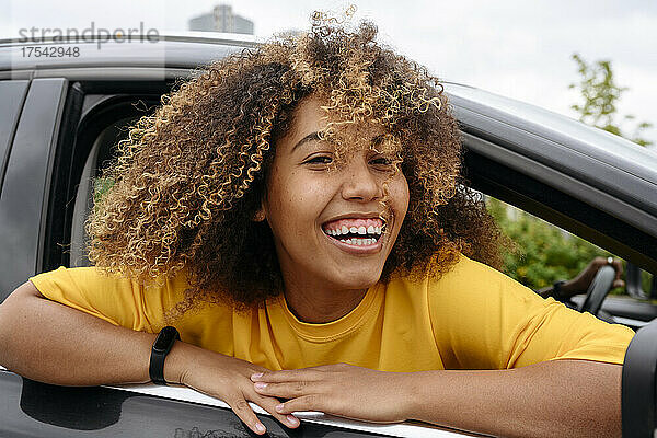 Junge Frau lacht und schaut aus dem Auto
