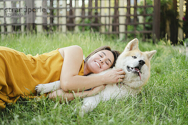 Smiling woman lying down with dog on grass