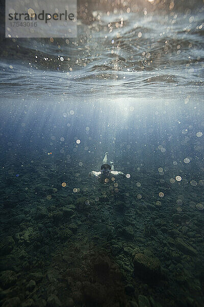 Mann schwimmt über dem Meeresboden unter Wasser