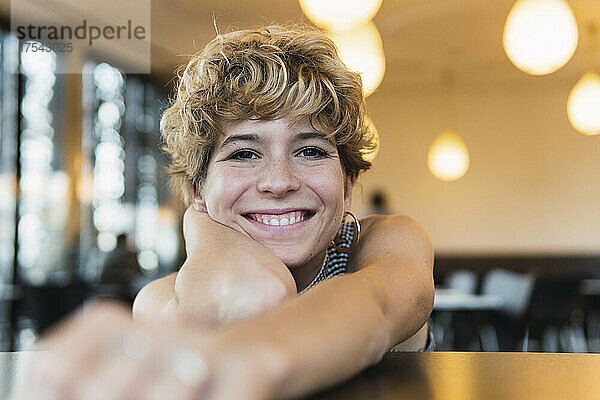 Smiling woman with hand on chin in coffee shop