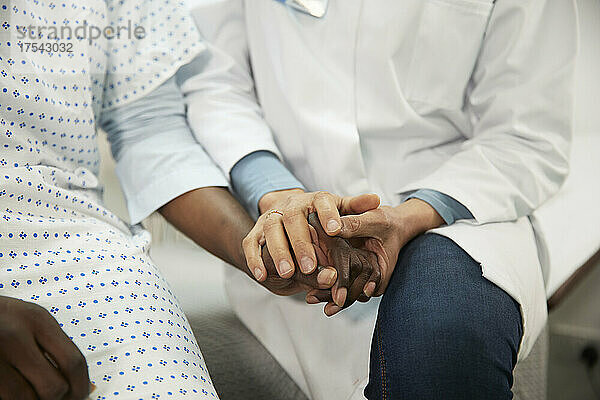 Arzt hält Händchen des Patienten im Krankenzimmer