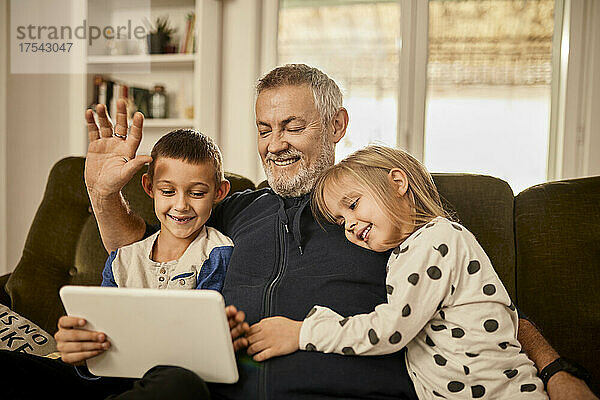 Enkelkinder nutzen Tablet-PC mit Großvater zu Hause