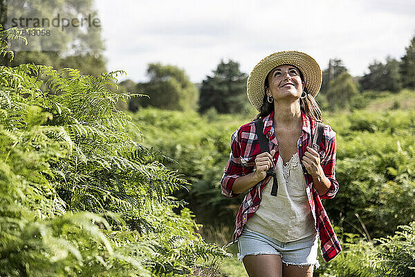 Smiling woman looking up walking in forest at Cannock Chase on sunny day