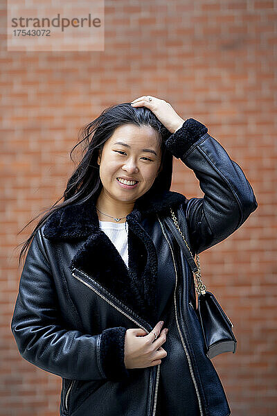 Smiling woman wearing jacket in front of wall