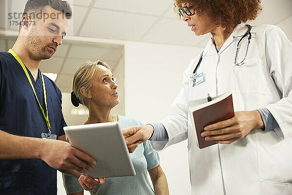 Arzt diskutiert mit Patient über Tablet-PC durch Krankenschwester im Krankenzimmer