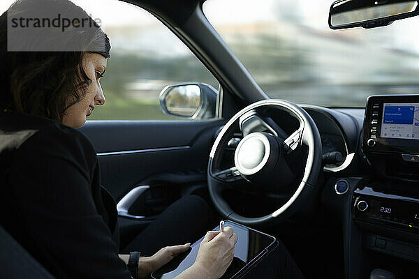 Geschäftsfrau nutzt Tablet-PC im fahrerlosen Auto