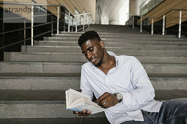 Smiling man reading book on steps