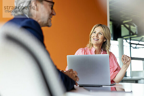 Lächelnde Geschäftsfrau  die mit einem Kollegen im Büro arbeitet