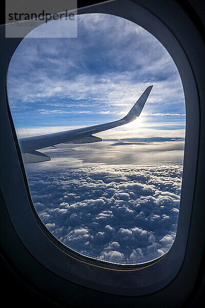Dicke Wolken  die durch das Fenster eines darüber fliegenden Flugzeugs gesehen werden