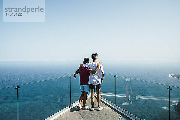 Young friends with arms around looking at sea from Mirador Del Balcon  Grand Canary  Canary Islands  Spain