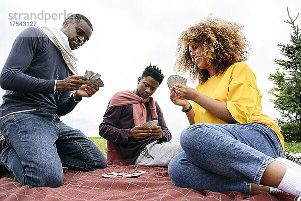 Junge Freunde spielen Karten im Park